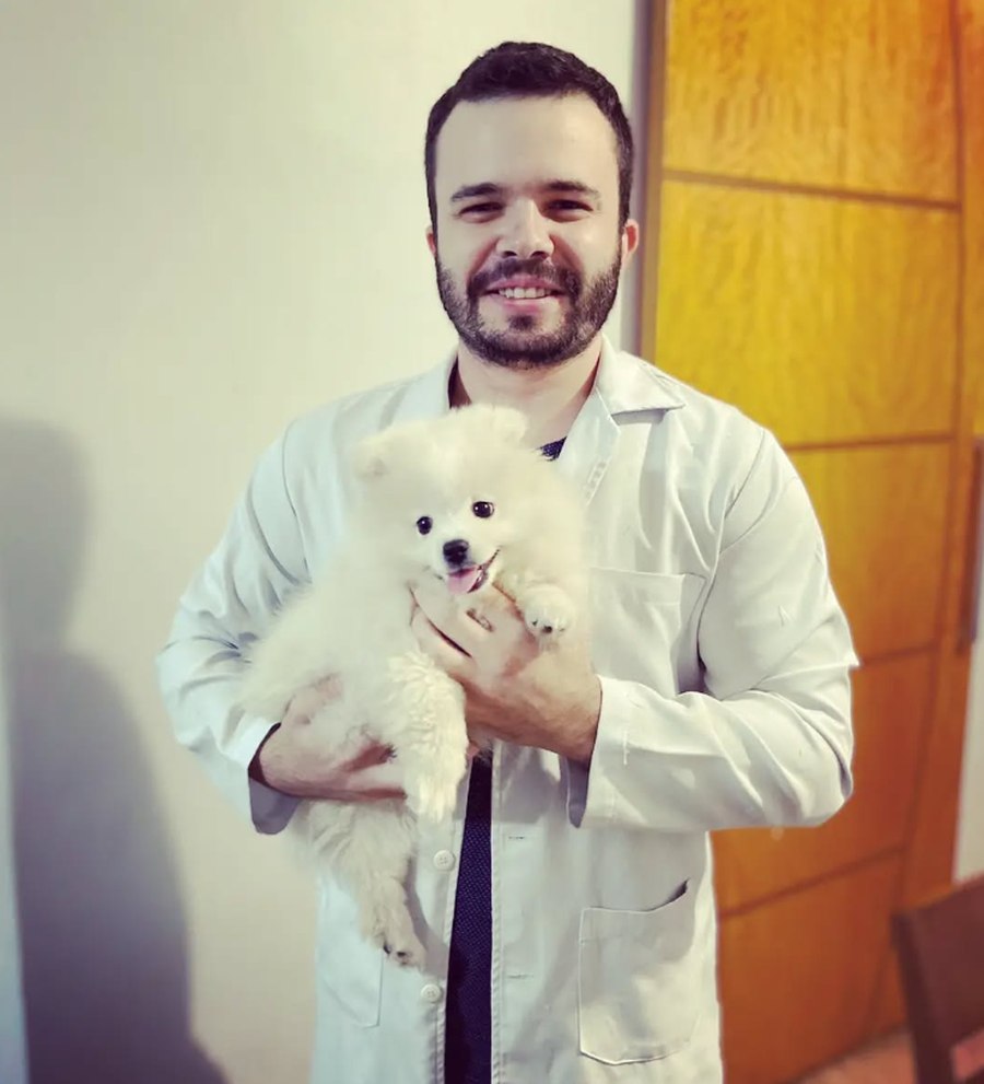 Dr. Guilherme Thimoteo sorrindo com um spitz alemão no colo, representando o cuidado no atendimento veterinário domiciliar